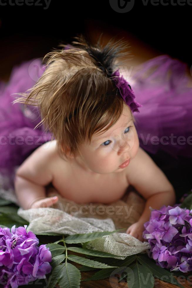 portret van een schattig klein meisje. baby ligt in de kleuren van paarse hortensia foto