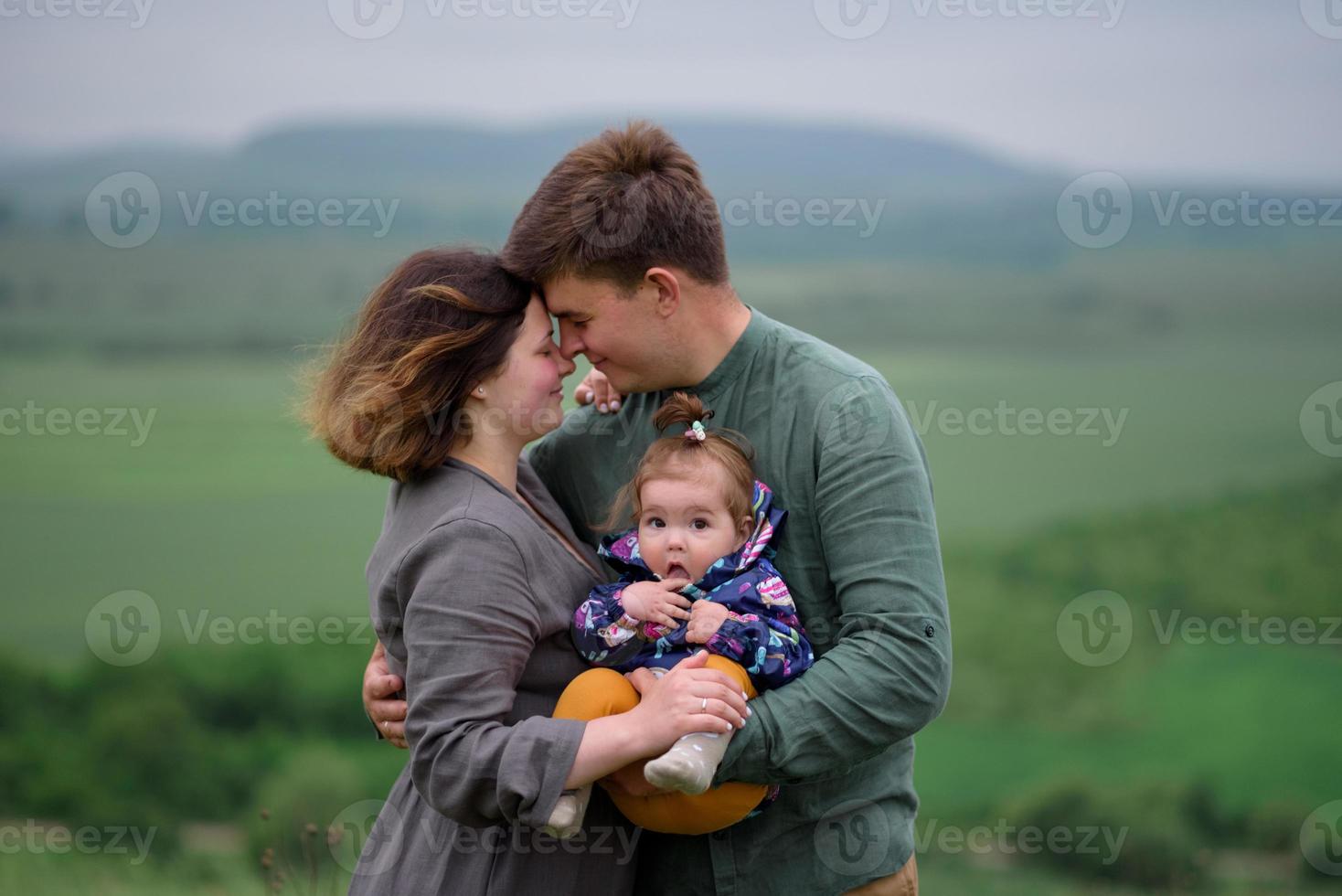 mama, papa en dochter. ouders houden de baby bij de hand en gaan naar de camera. foto