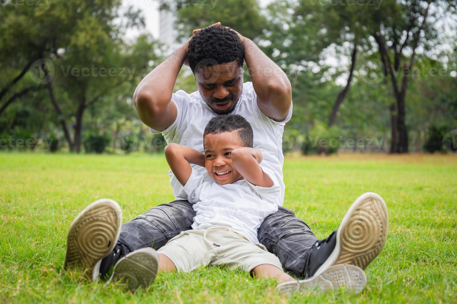 vrolijke Afro-Amerikaanse vader en zonen die in het park spelen, geluksfamilieconcepten foto