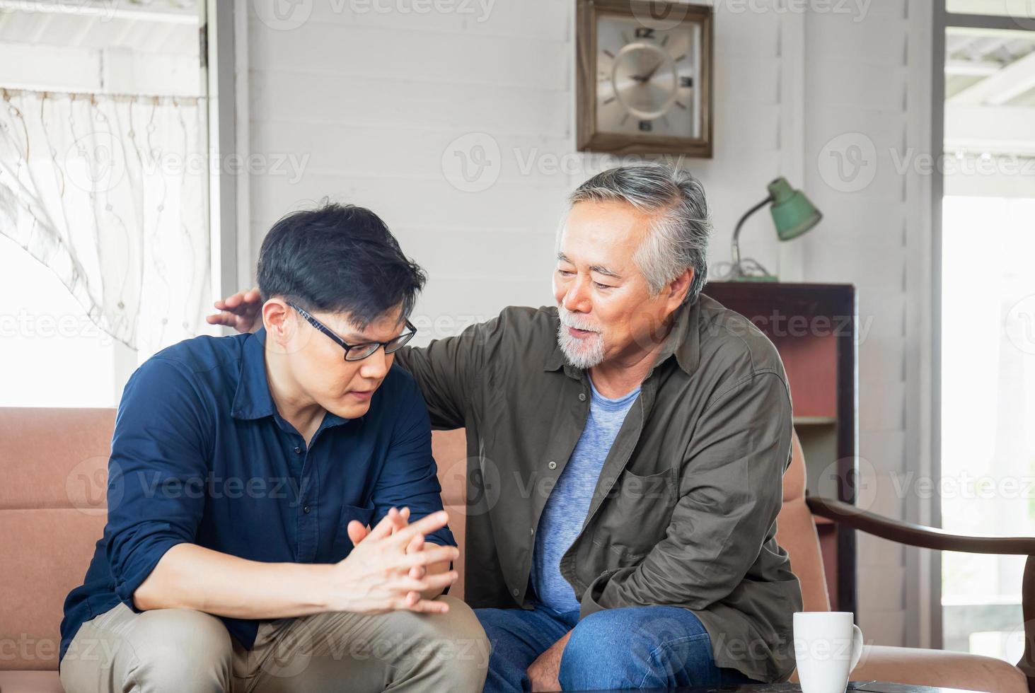 senior aziatische vader geeft advies volwassen zoon in woonkamer, geluk familieconcepten foto