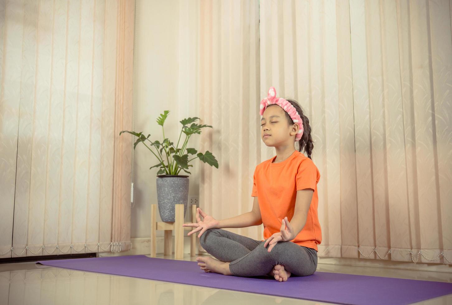 gelukkig klein schattig meisje dat thuis yoga beoefent, sportconcept voor kinderen foto