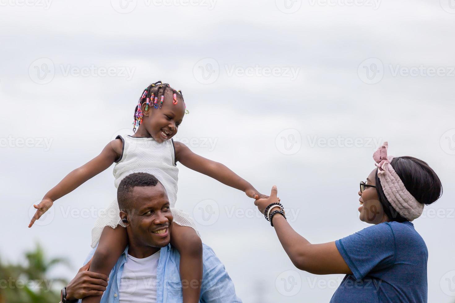 gelukkige vader moeder en dochter spelen samen buiten, vrolijke Afro-Amerikaanse familie genieten in het park, geluk familieconcepten foto