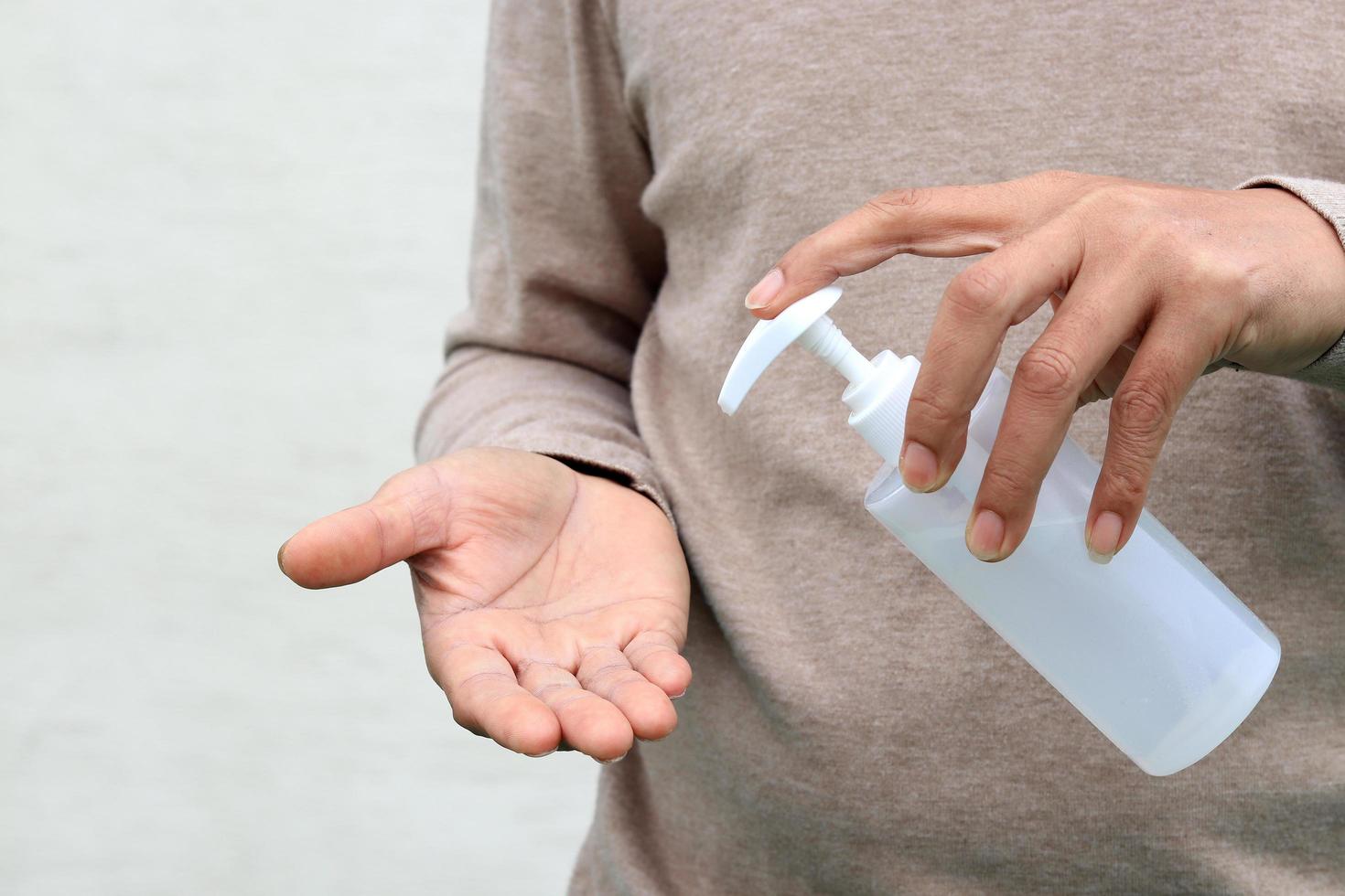 man die handpersfles gebruikt en op alcohol gebaseerde ontsmettingsmiddel op andere handen giet, om het virus covid-19 te voorkomen foto