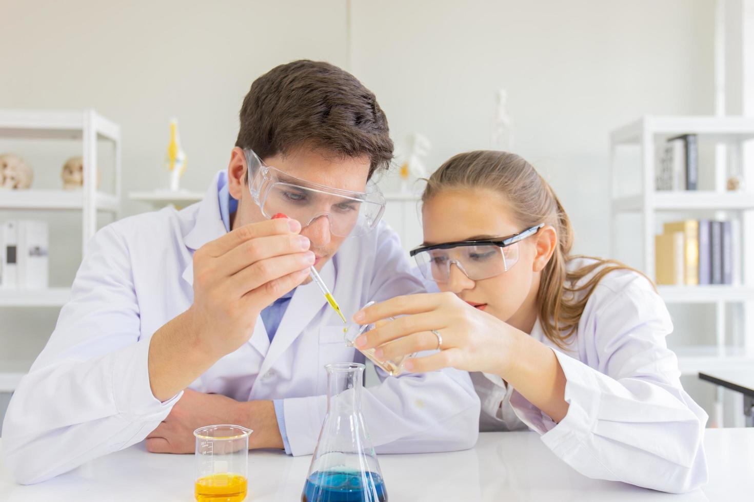 mannelijke en vrouwelijke wetenschappers werken in een wetenschappelijk laboratorium met verschillende apparatuur in het laboratorium. foto