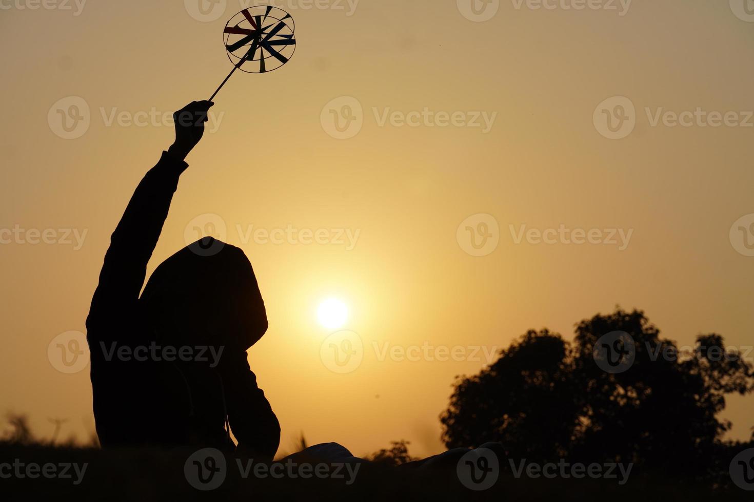 gelukkige jonge jongen met een speelgoedbloemblaadje op de achtergrond van een zonsondergang boven een tarweveld foto