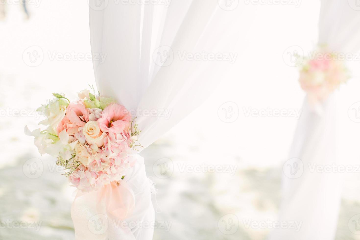 kleurrijk roze en lichtgroen bloemstuk vastgebonden aan een boog in een huwelijksceremonie foto