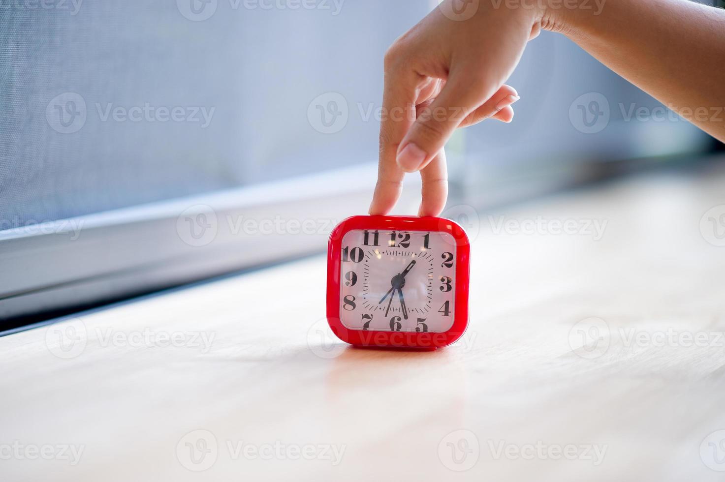hand en rode wekker die elke ochtend het alarm laat zien, het concept van stiptheid foto
