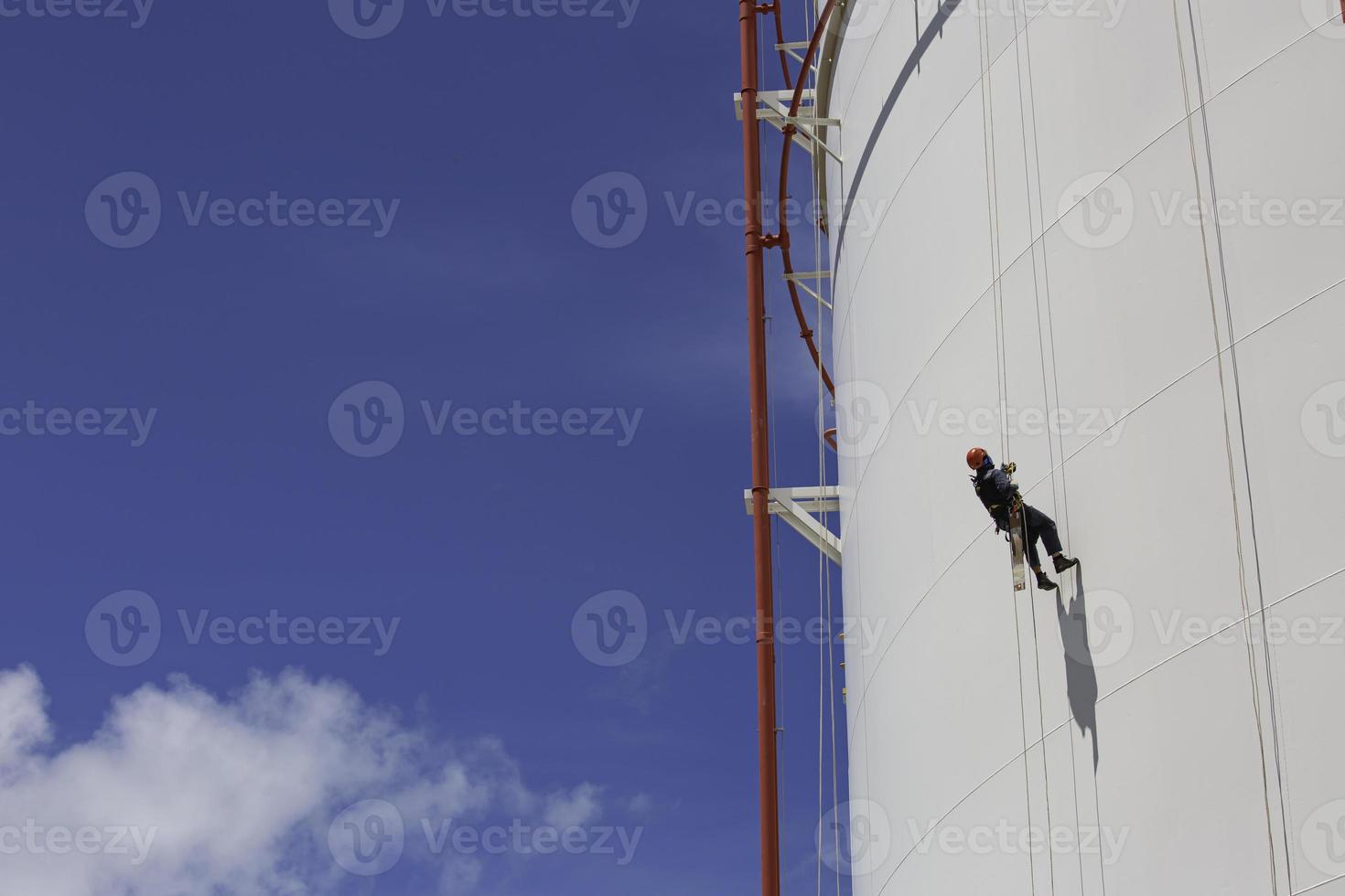 mannelijke werknemer naar beneden hoogte tank schaal plaat touw ladder toegang veiligheidsinspectie van dikte opslagtank foto