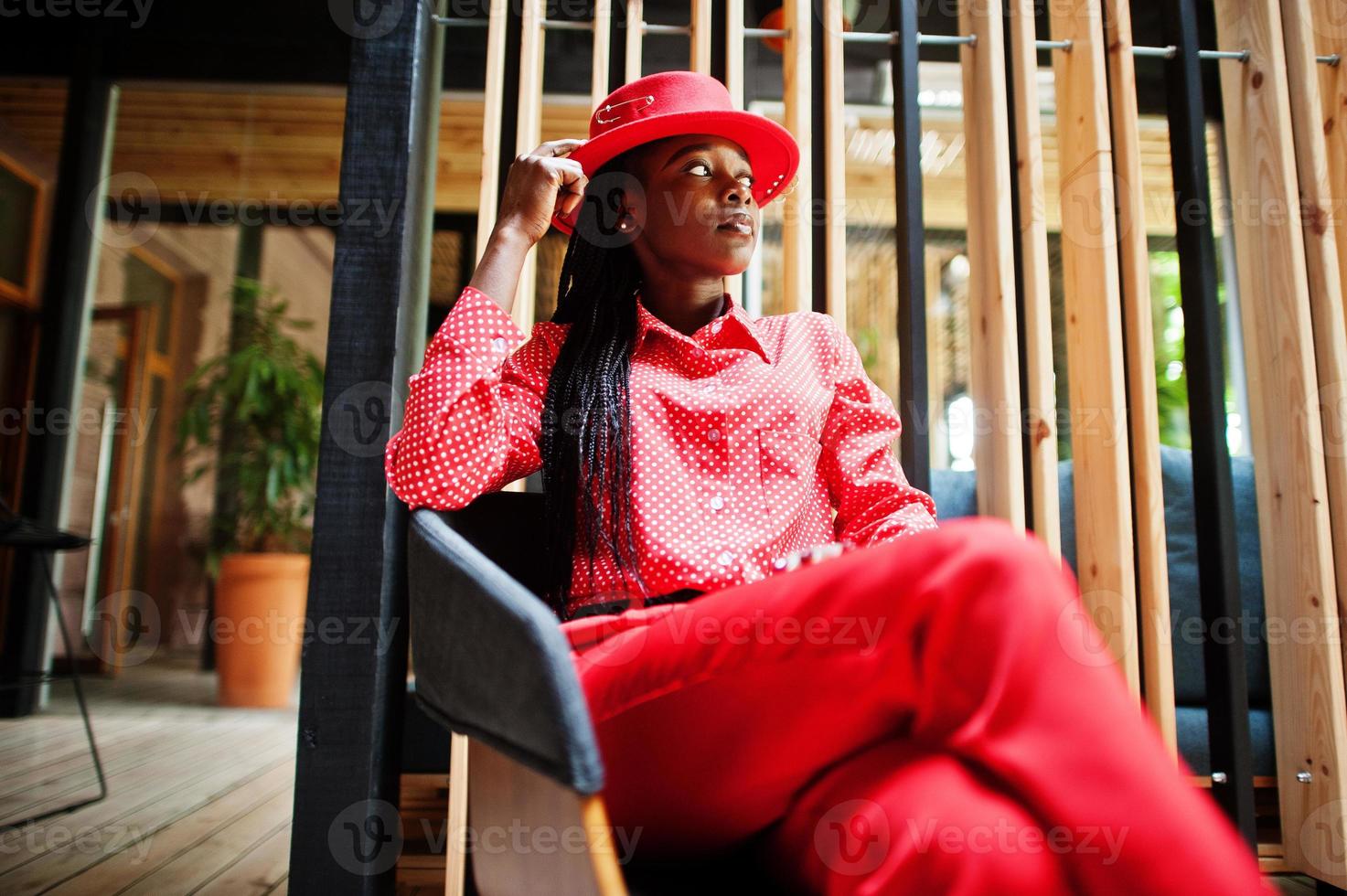 mooie vlechten zakelijke afro-amerikaanse dame heldere bazige persoon vriendelijke slijtage kantoor rood shirt, hoed en broek. foto