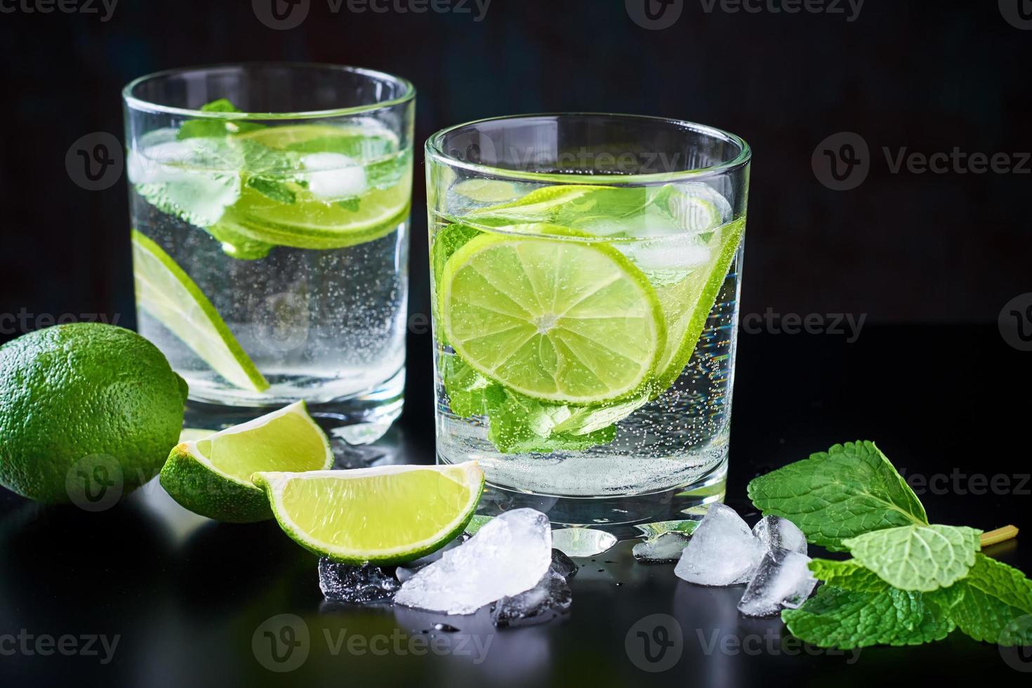 zomerdrankje limonade-mojito met limoen, munt en ijs op een zwarte achtergrond foto