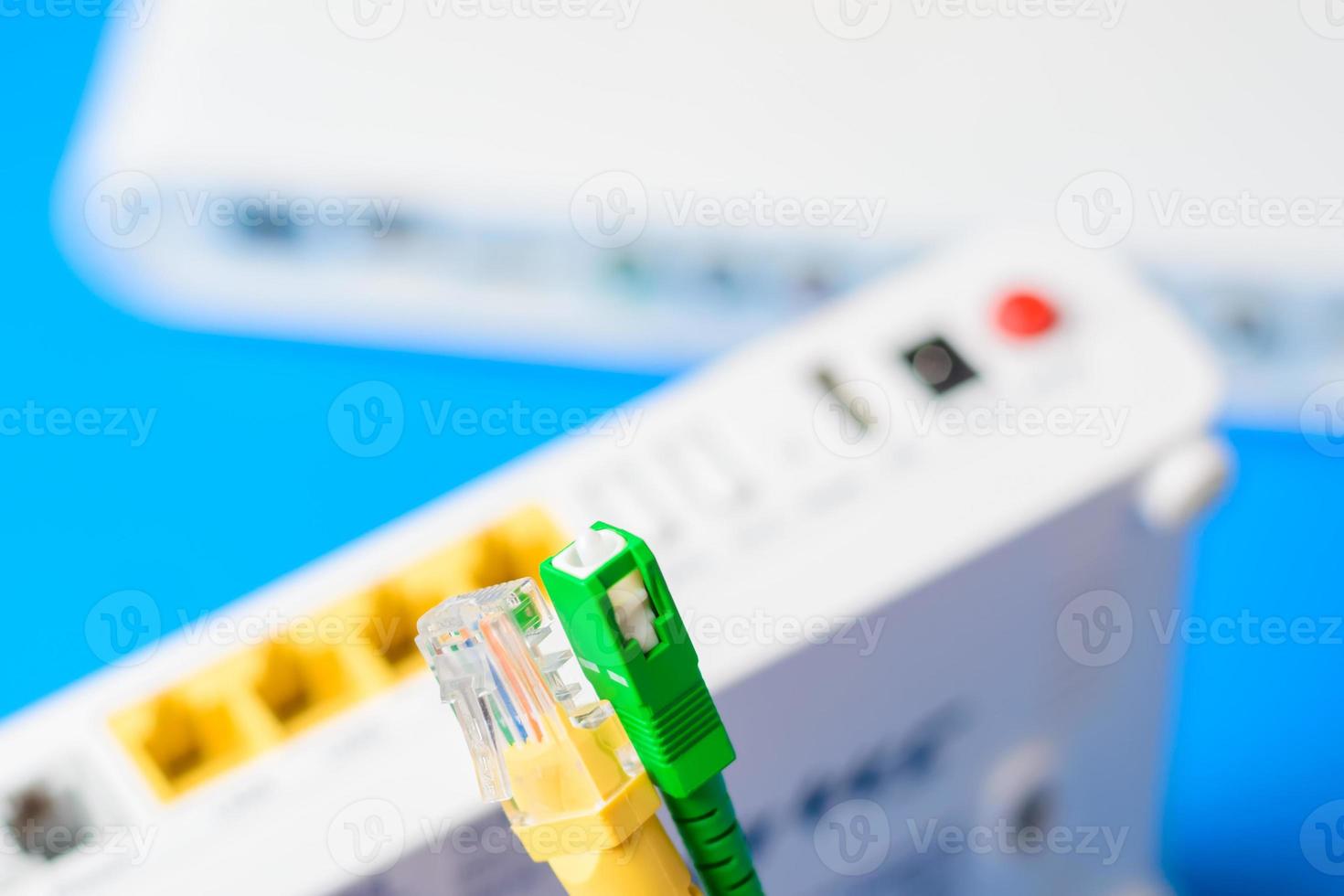 glasvezel- en netwerkkabels met draadloze internetrouter op een blauwe achtergrond foto