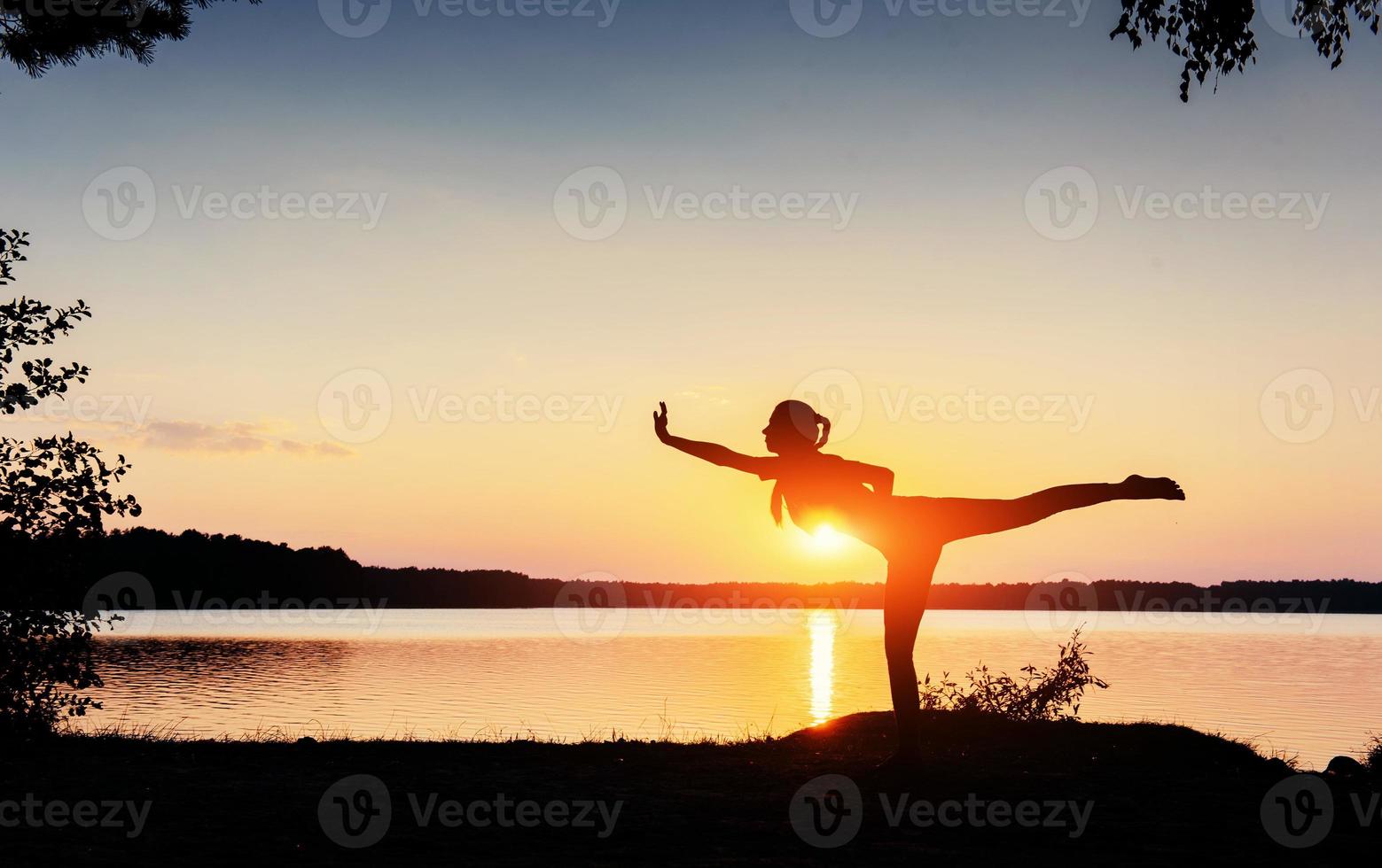 vrouw sportieve verschijning bij zonsondergang in de buurt van het water foto
