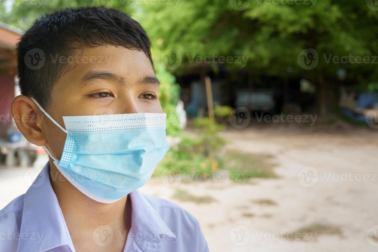 gemaskerde mannelijke student kijkt ernaar uit, voorkom coronavirus foto