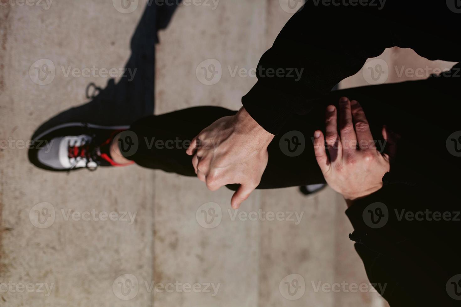 man in een zwart trainingspak strekt zijn benen foto