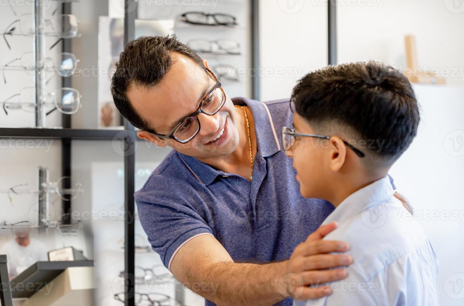 Indiase vader en zoon kiezen brillen in optiekwinkel foto