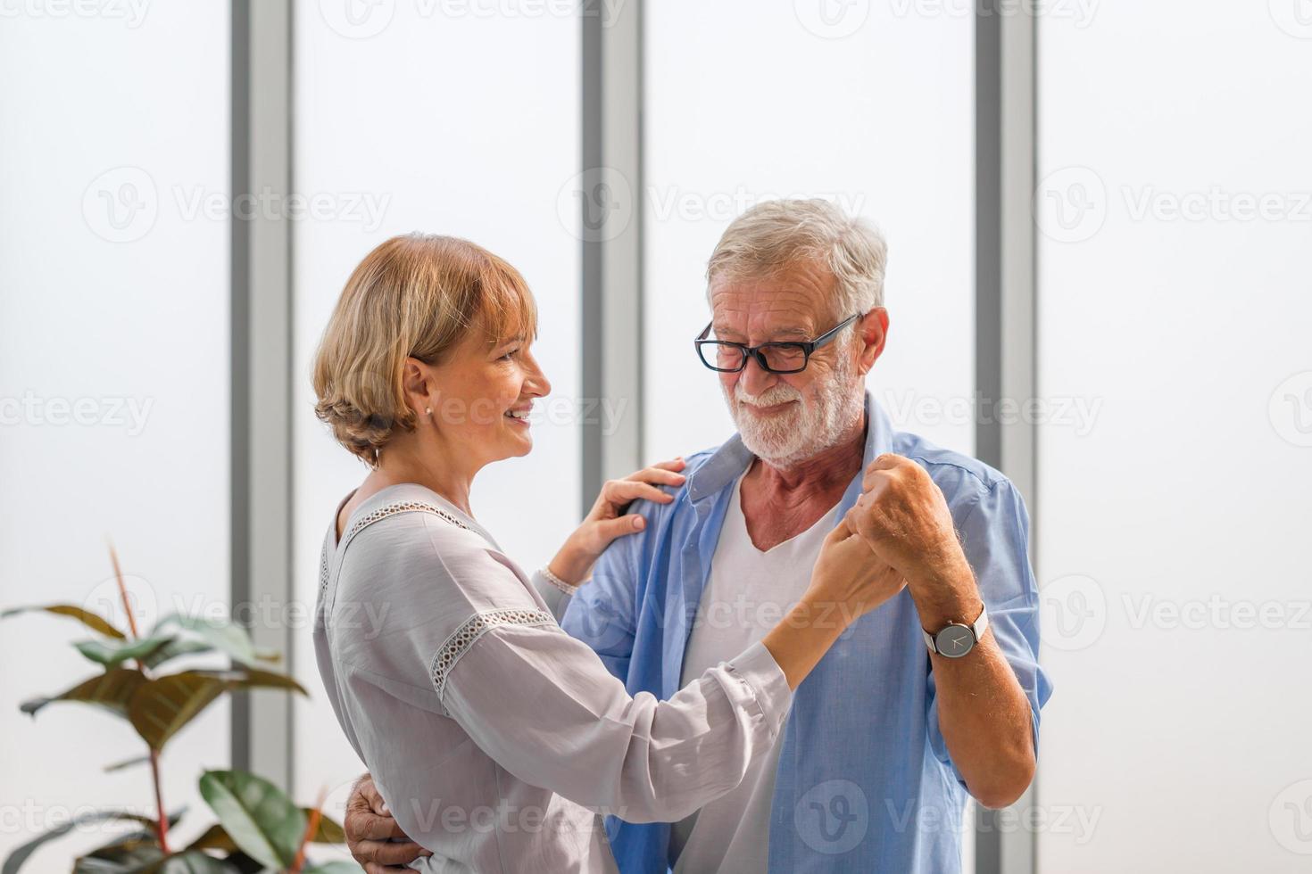 portret van een gelukkig senior koppel dat danst in de woonkamer, een oudere vrouw en een man die danst, gelukkige familieconcepten foto