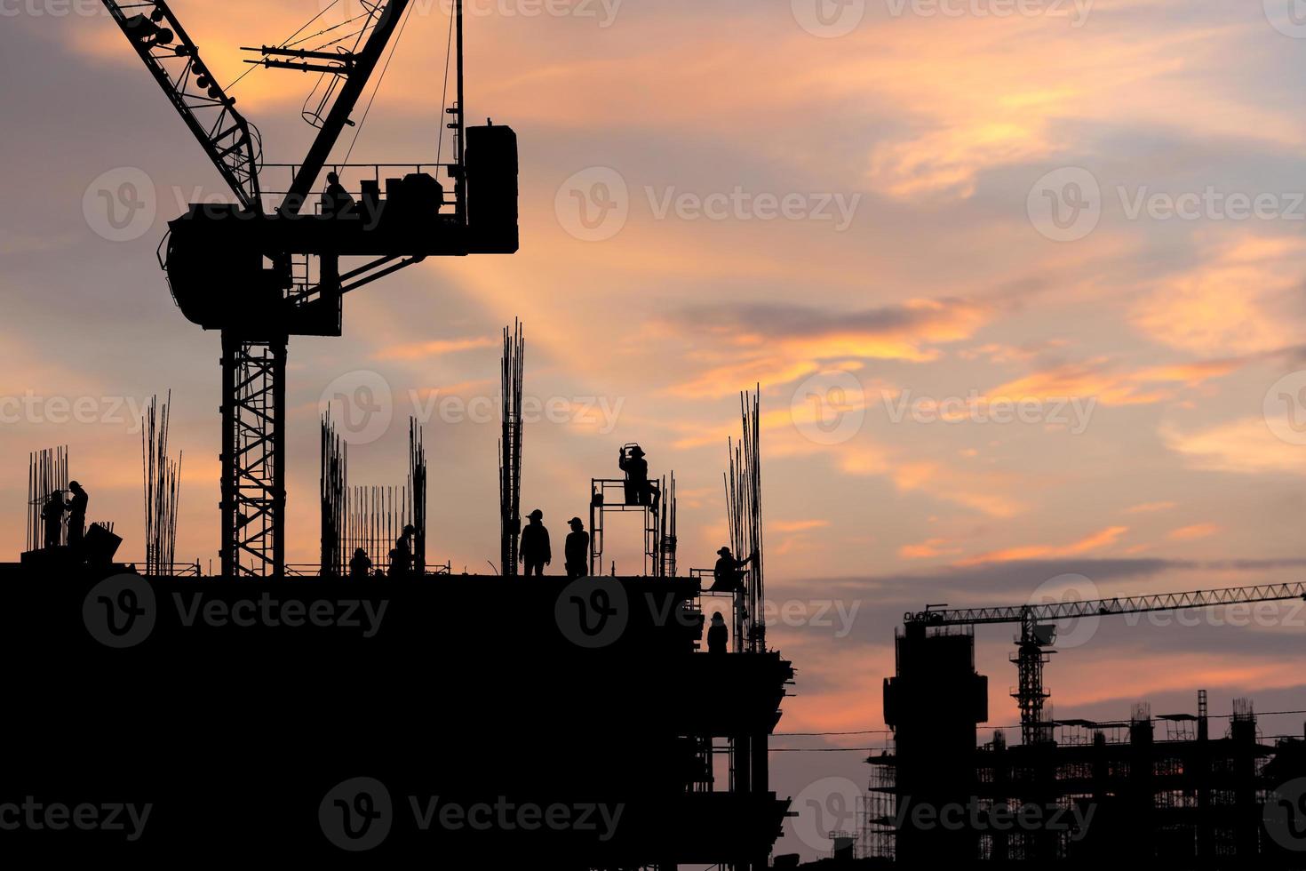 silhouet van arbeidersteam op bouwplaats, bouwwerf bij zonsondergang in de avondtijd foto