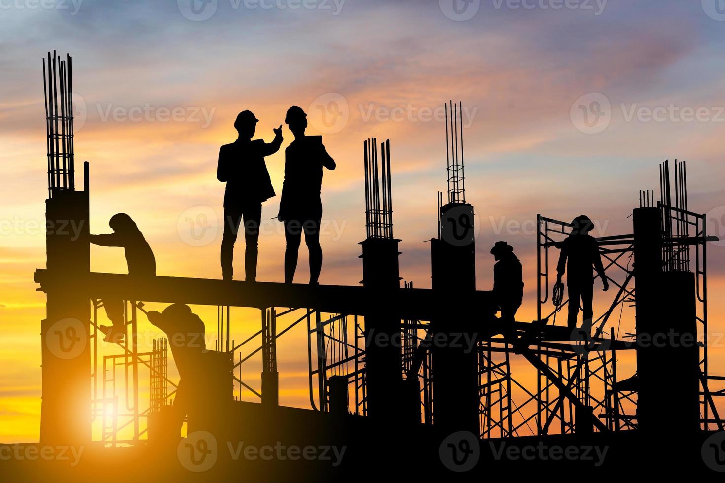 silhouet van ingenieur en werknemer op bouwplaats, bouwplaats bij zonsondergang in de avondtijd foto