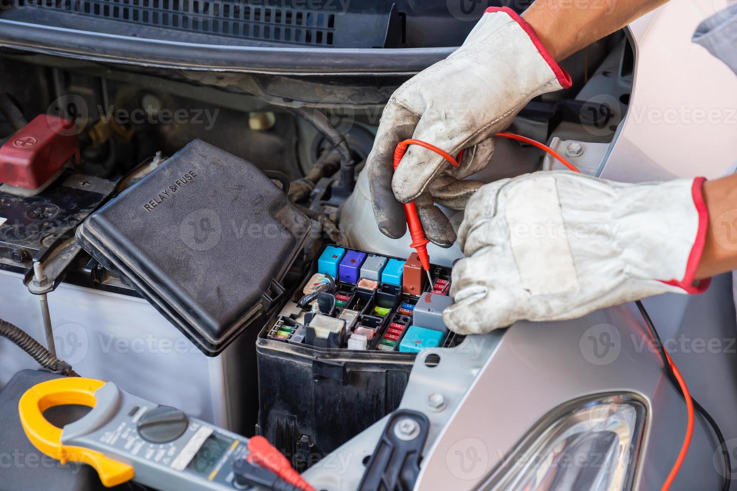 automonteur bezig met het controleren van de motor van een auto, relais en zekering in de garage van de mechanica, reparatie- en onderhoudsservice foto