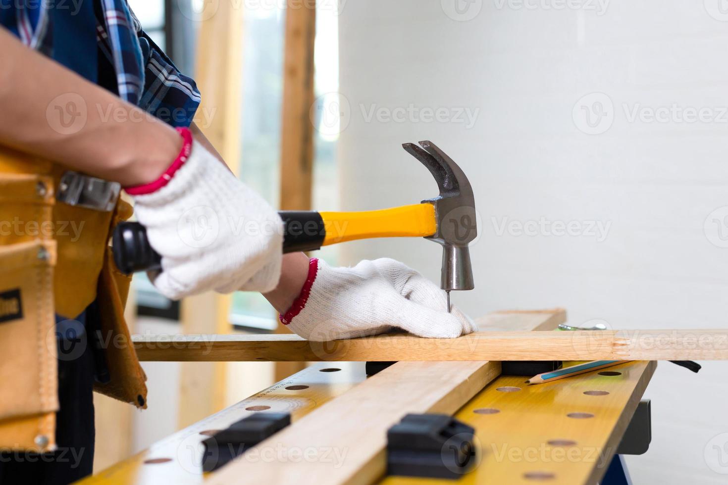 ambachtsman met hamer gespijkerd in werkplaats, timmerman met hamer sloeg een spijker voor montage hout in een timmerwerkplaats foto