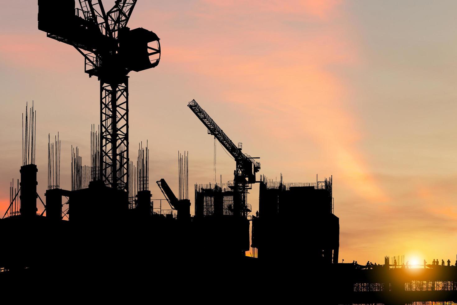 silhouet van arbeidersteam op bouwplaats, bouwwerf bij zonsondergang in de avondtijd foto