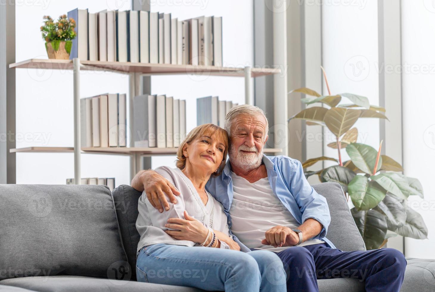 oudere vrouw en een man ontspannen op een gezellige bank thuis, gelukkig senior paar in de woonkamer, gelukkige familieconcepten foto