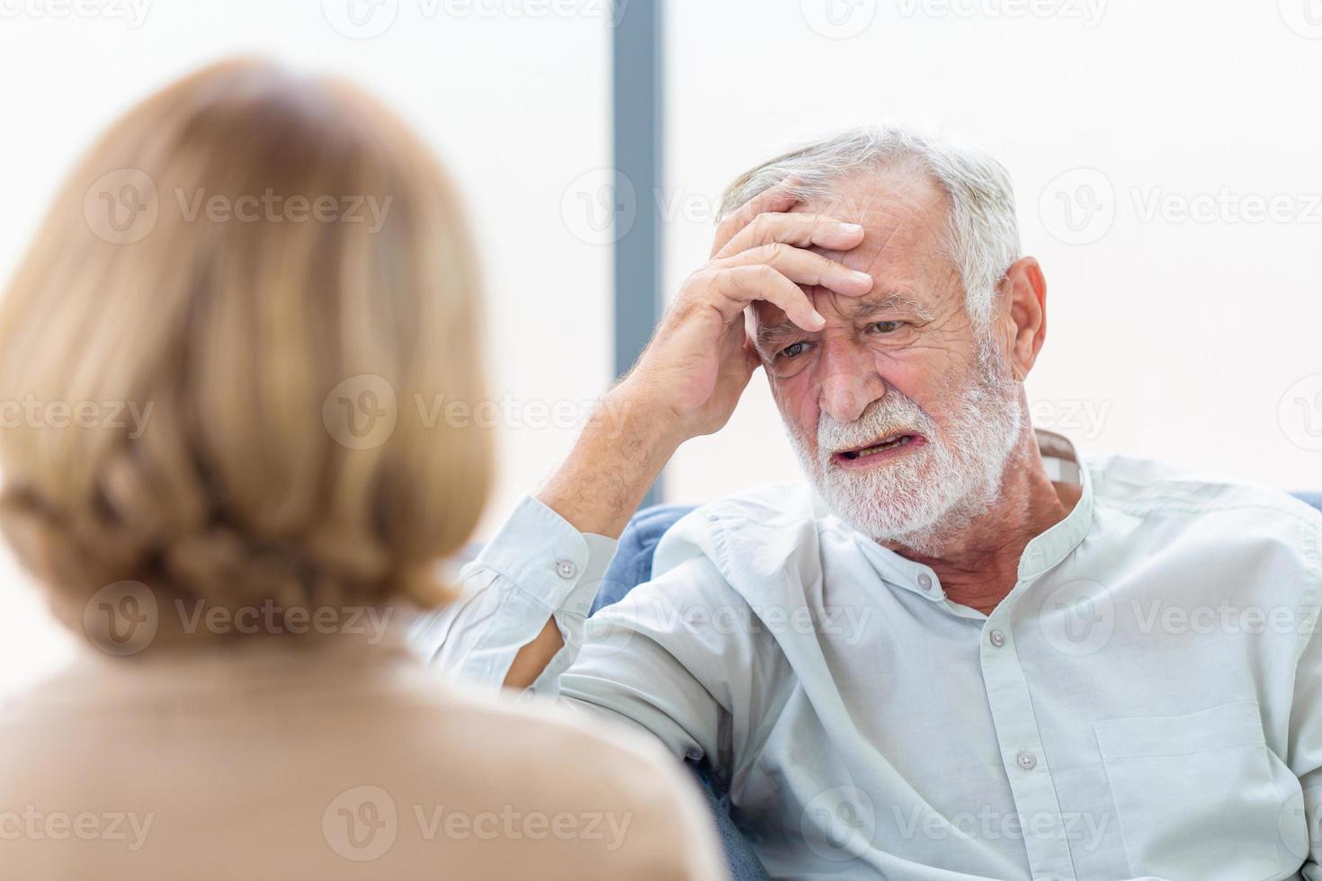 Senior paar in woonkamer, close-up hoofdschot serieuze oudere man raadplegen senior vrouw op gezellige bank thuis, ouderen medische zorgconcepten foto