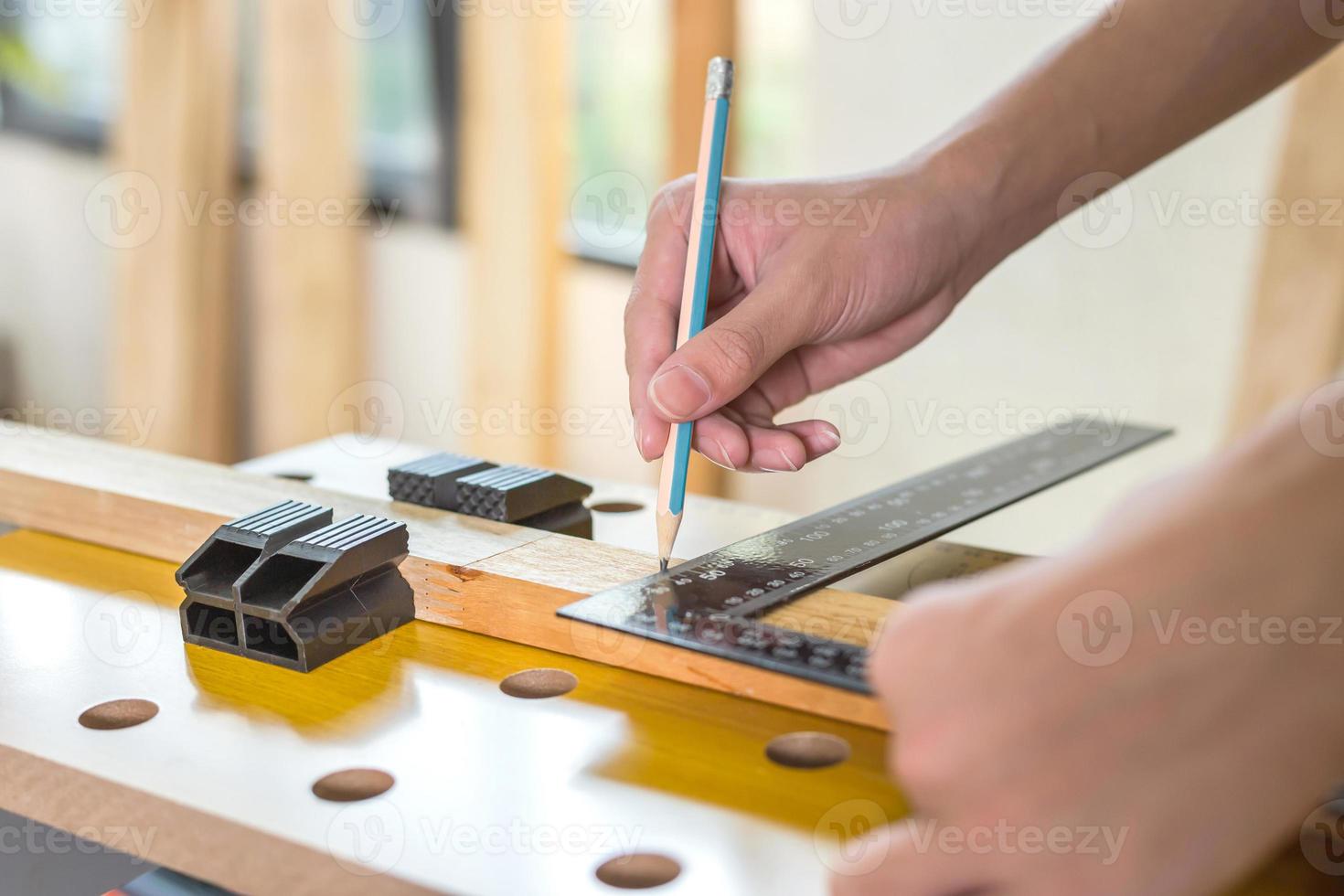 timmerman markeerpunt op plank in de ambachtswerkplaats, man meet een houten bord met een liniaal en markeert met potlood foto