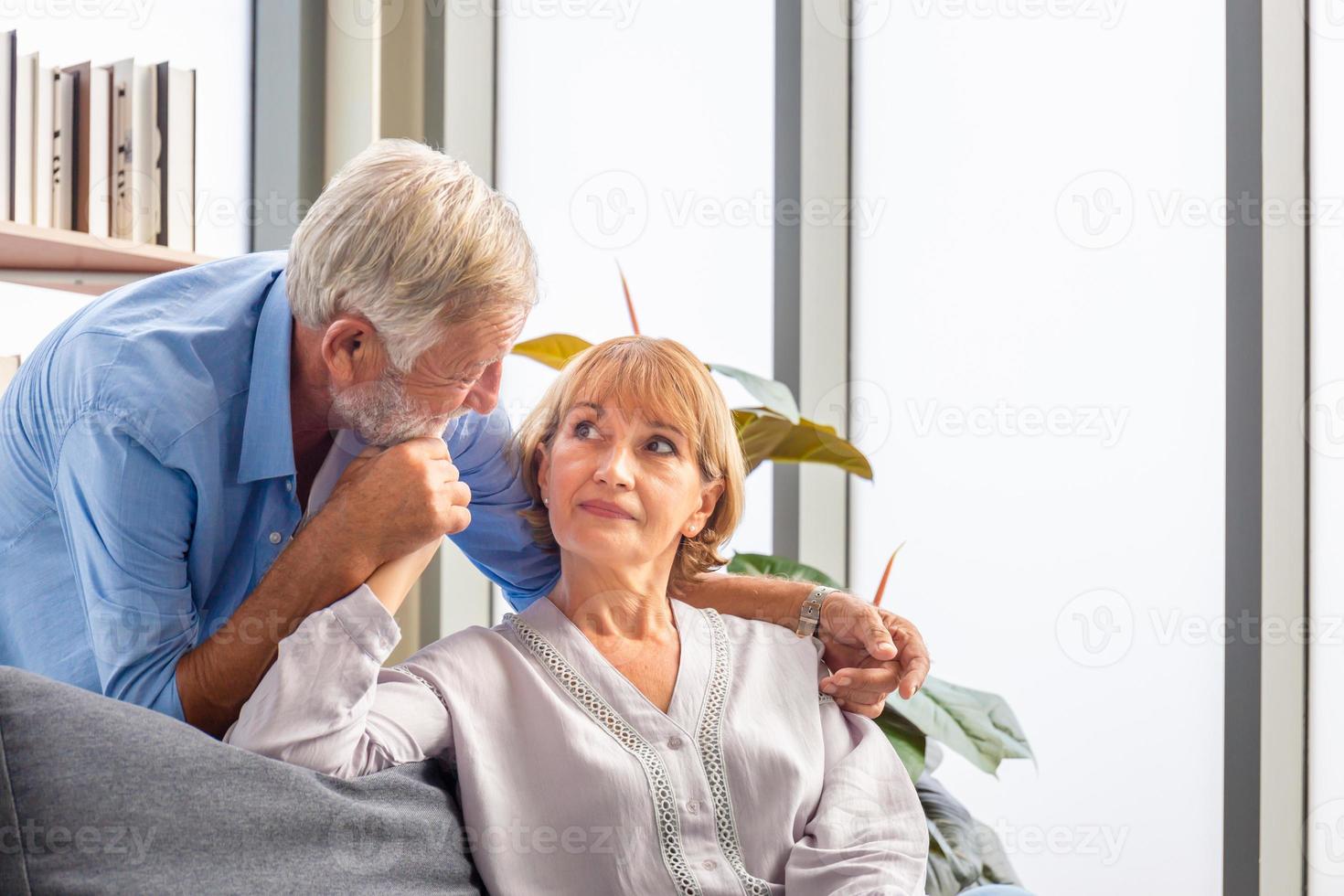 portret van een gelukkig senior koppel in de woonkamer, een oudere vrouw en een man die thuis op een gezellige bank ontspant, concepten voor gelukkige gezinnen foto