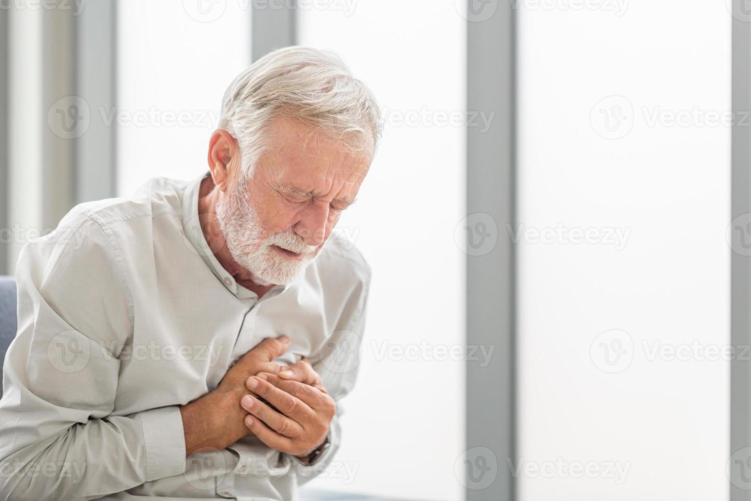 Senior man drukt hand op borst heeft hartaanval lijdt aan ondraaglijke pijn, volwassen man met pijn op hart in woonkamer foto