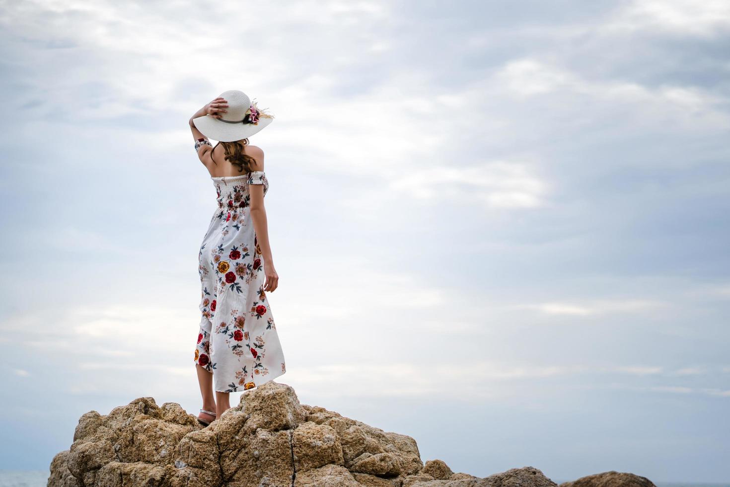 volwassen azië vrouw reist naar de zee en staat ontspannen op de rots foto