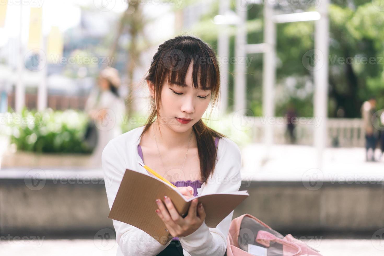 jonge volwassen Aziatische student vrouw zitten schrijven op notebook. foto