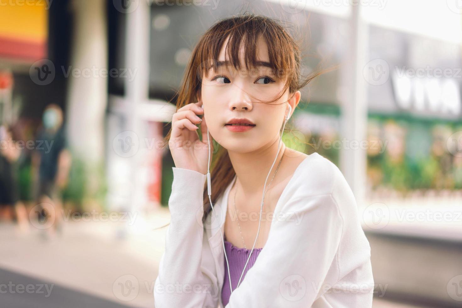 Aziatische tiener student vrouw gebruik oortelefoon luisteren muziek op buiten. foto