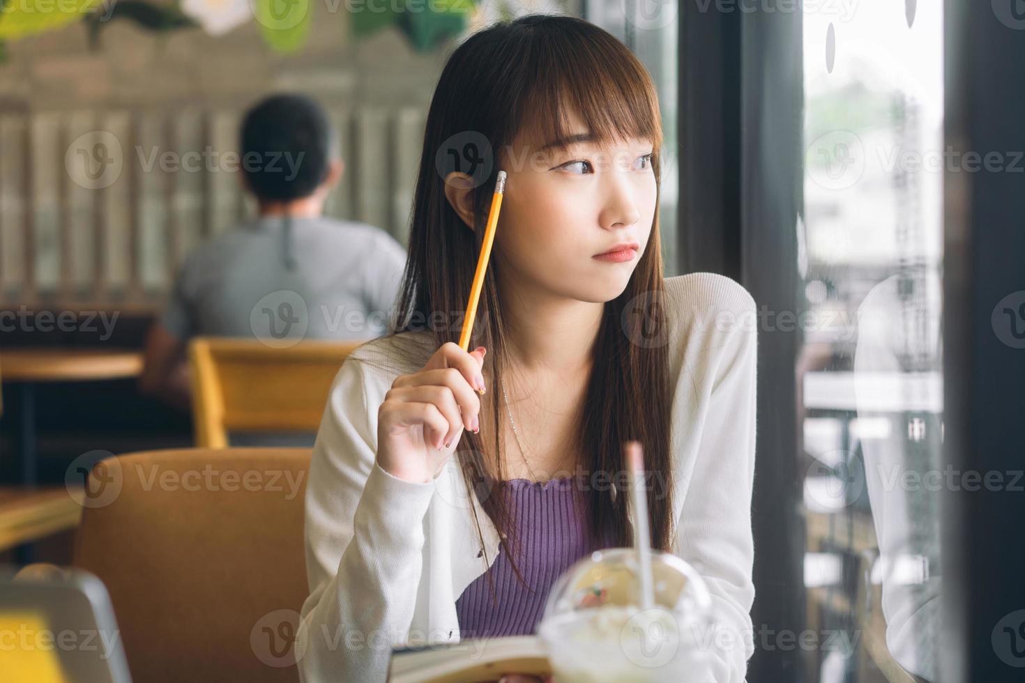 jonge Aziatische tiener student vrouw. studeren en huiswerk maken in café. foto