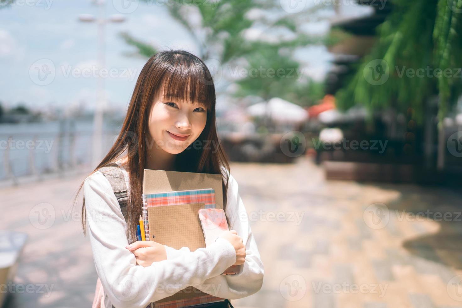 portret van gelukkige jonge volwassen Aziatische student vrouw met notebook. foto