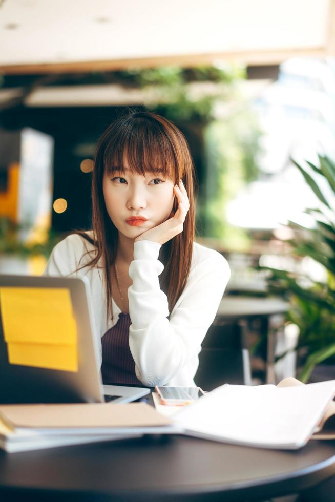 Aziatische tiener student vrouw studeren en werken online in café op dag. foto