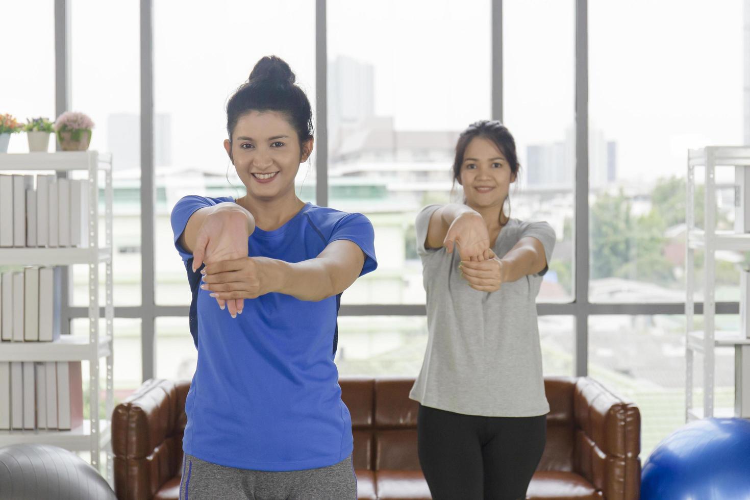 twee Aziatische vrouwen van middelbare leeftijd doen yoga in hun huis. foto