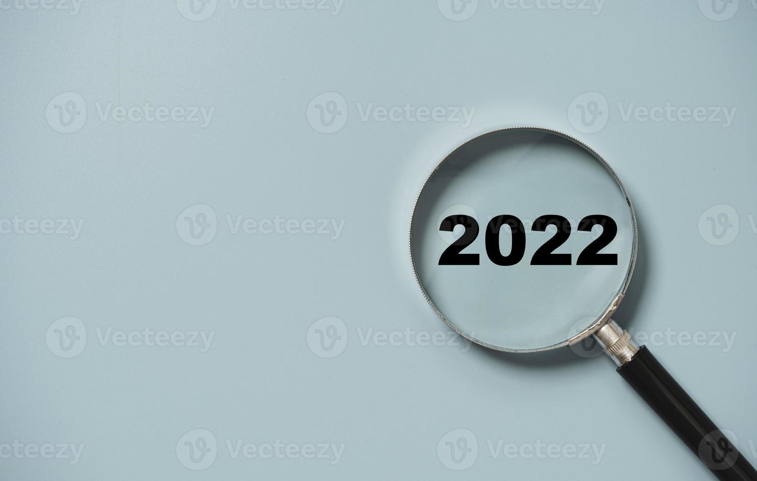 2022 jaar nummer insider van vergrootglas op blauwe achtergrond voor focus nieuwjaar bedrijfsconcept. foto