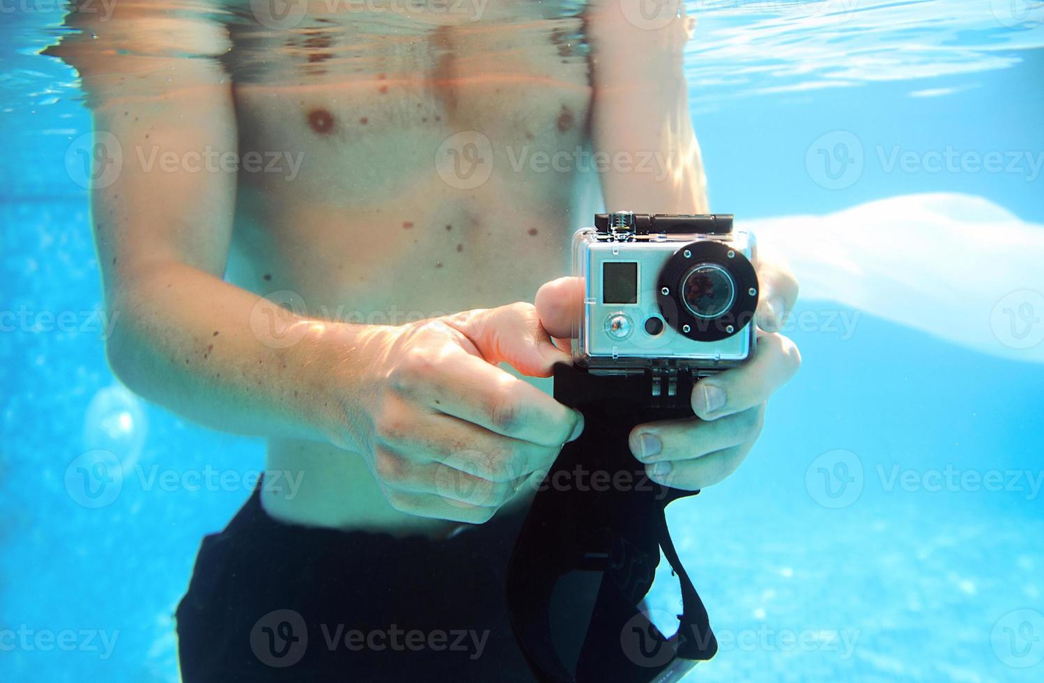 jonge man die in de zomer onderwater foto's maakt in het zwembad foto