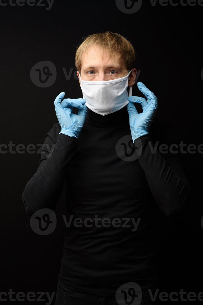 bescherming tegen besmettelijke ziekte, coronavirus. man met hygiënisch masker om infectie te voorkomen 2019-ncov. man's paniek man trekt beschermende handschoenen aan foto