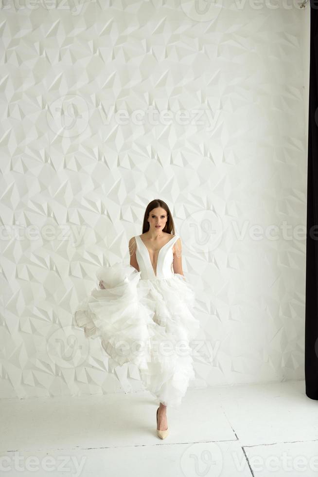 portret van een mooie bruid in volle groei in de studio op een witte achtergrond. de vrouw staat met haar rug en kijkt in het frame. foto