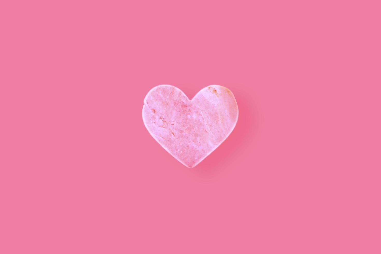 een hartvormige steen op een roze achtergrond. foto