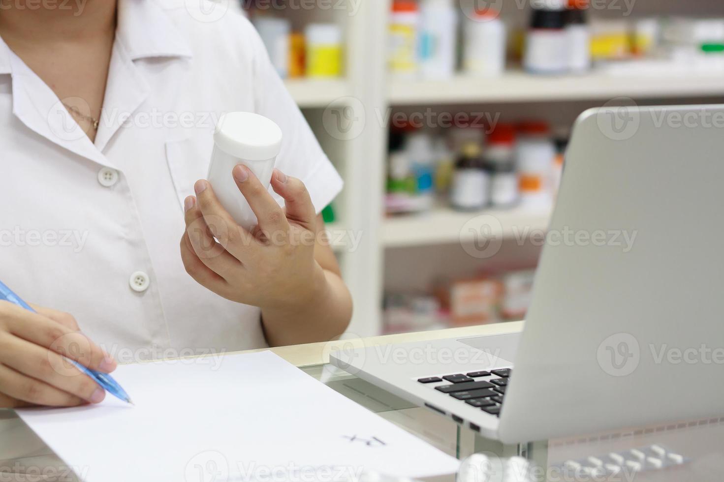 apotheker met laptopcomputer en medicatie in de apotheek foto