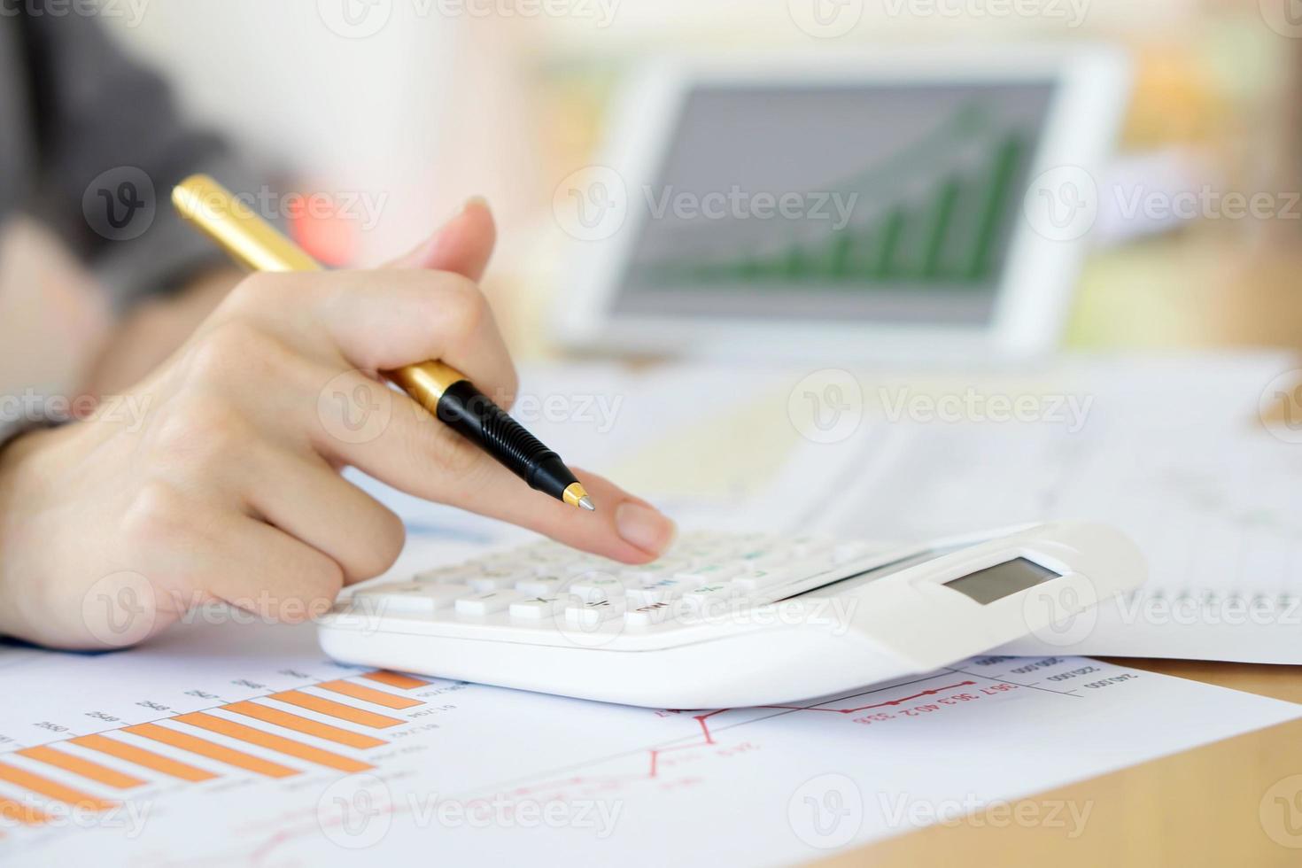 close-up van zakenvrouw die financieel rapport analyseert met rekenmachine op houten foto