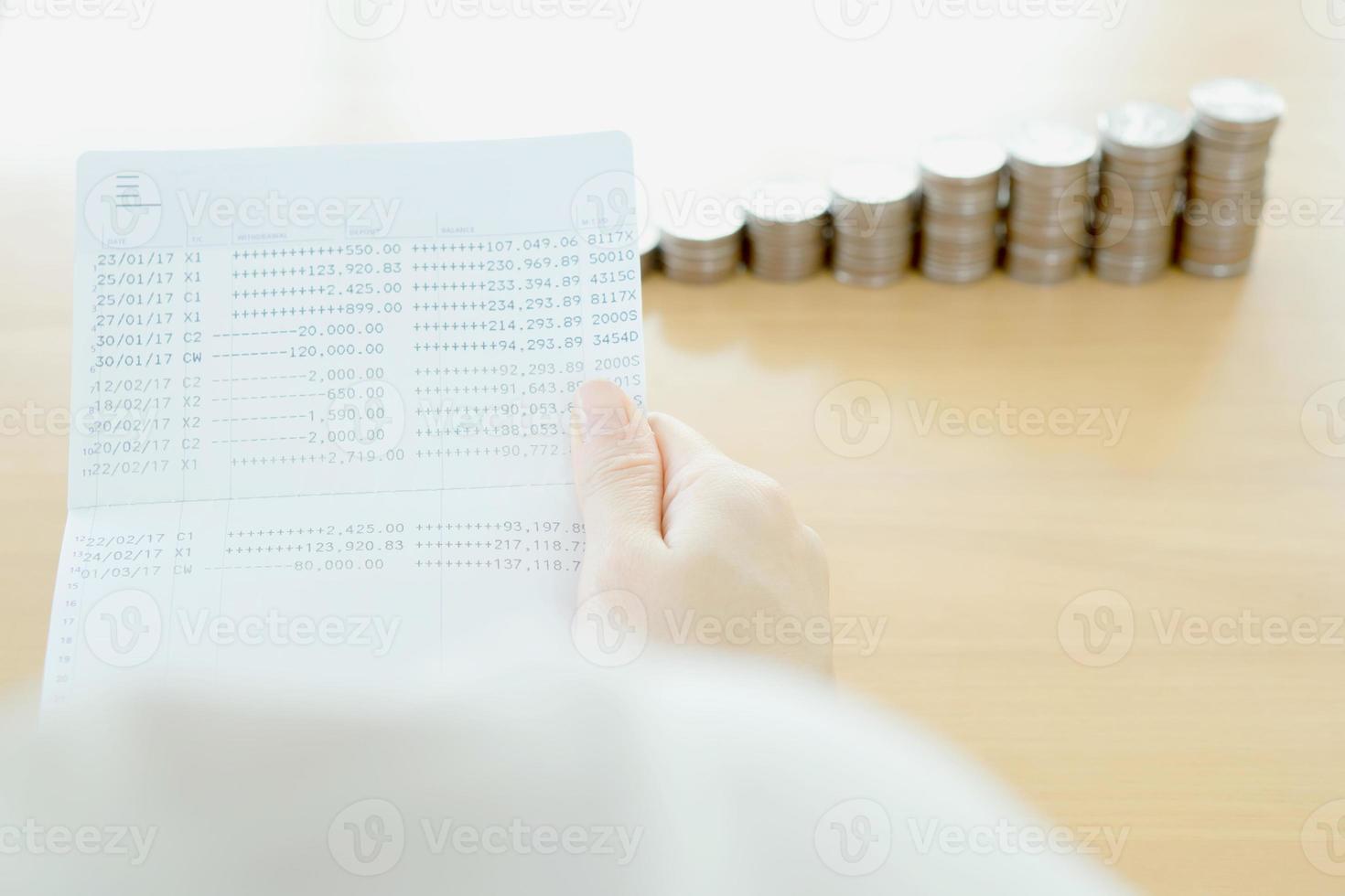 vrouw houdt bankboekje bij de hand, munten achtergrond foto