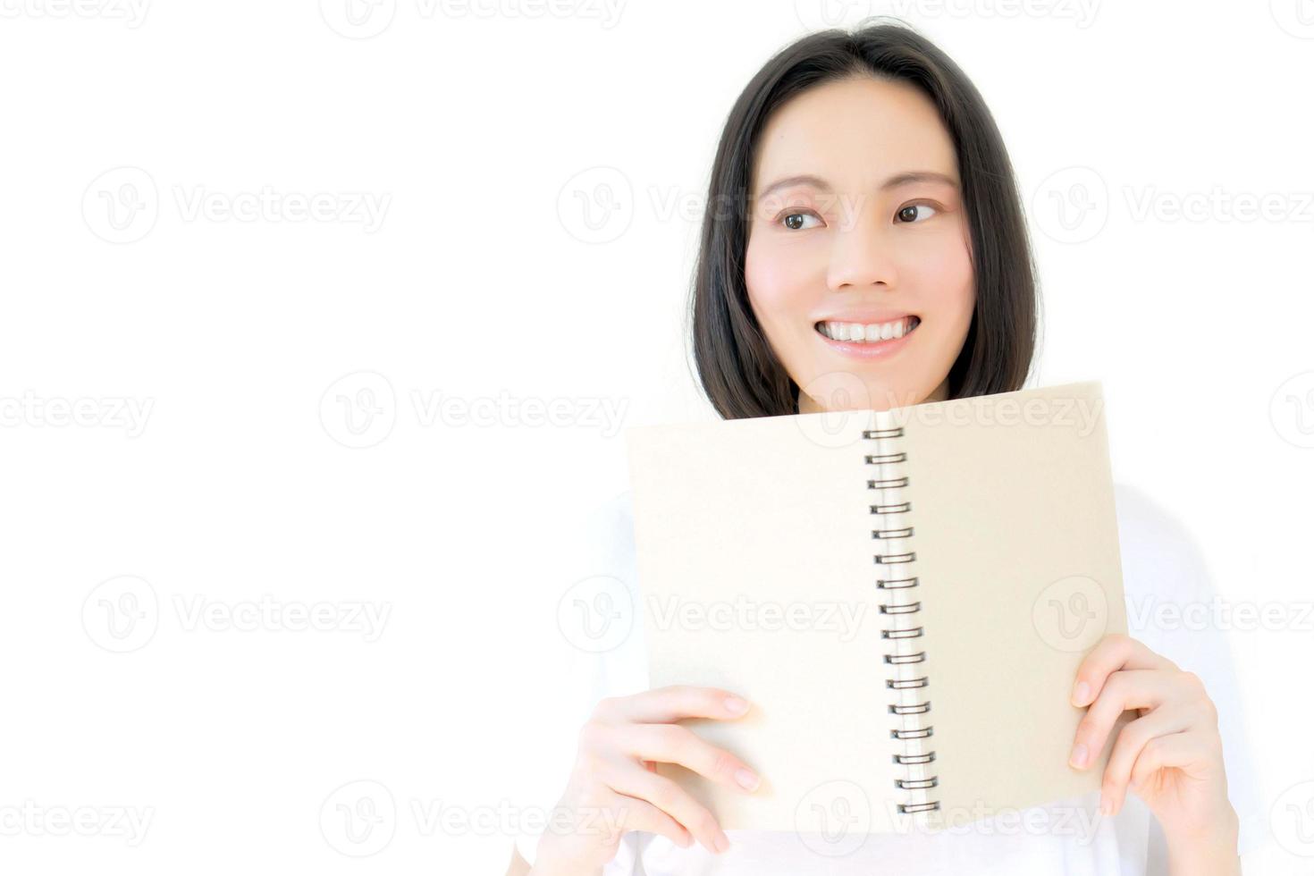 blanke meisjesglimlach en verbergt zijn gezicht achter een boek. studioportret van blond model foto