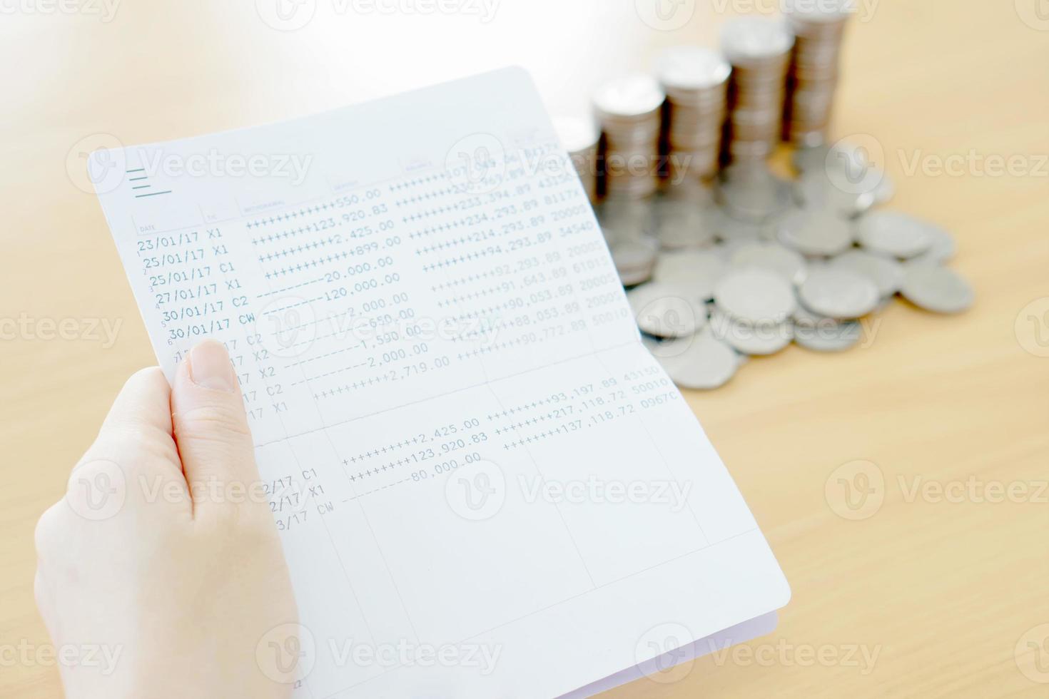 vrouw houdt bankboekje bij de hand, munten achtergrond foto