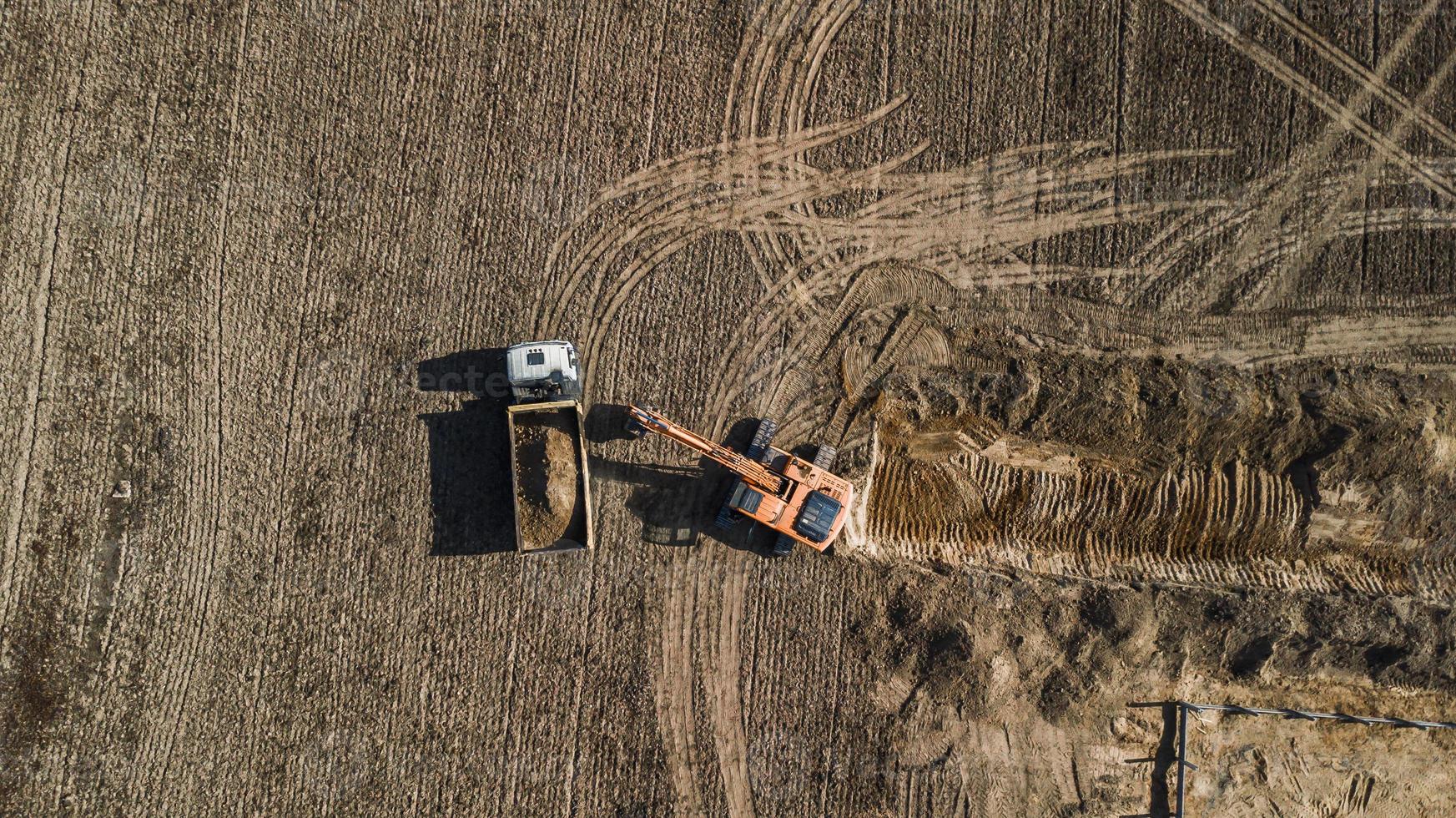 graafmachine laadt vrachtwagen luchtfoto van bovenaf met drone foto