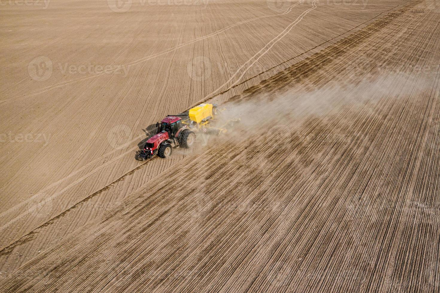 luchtfoto van tractor met gemonteerde zaaimachine die direct zaaien van gewassen op geploegd landbouwveld uitvoert. boer gebruikt landbouwmachines voor het plantproces, bovenaanzicht foto