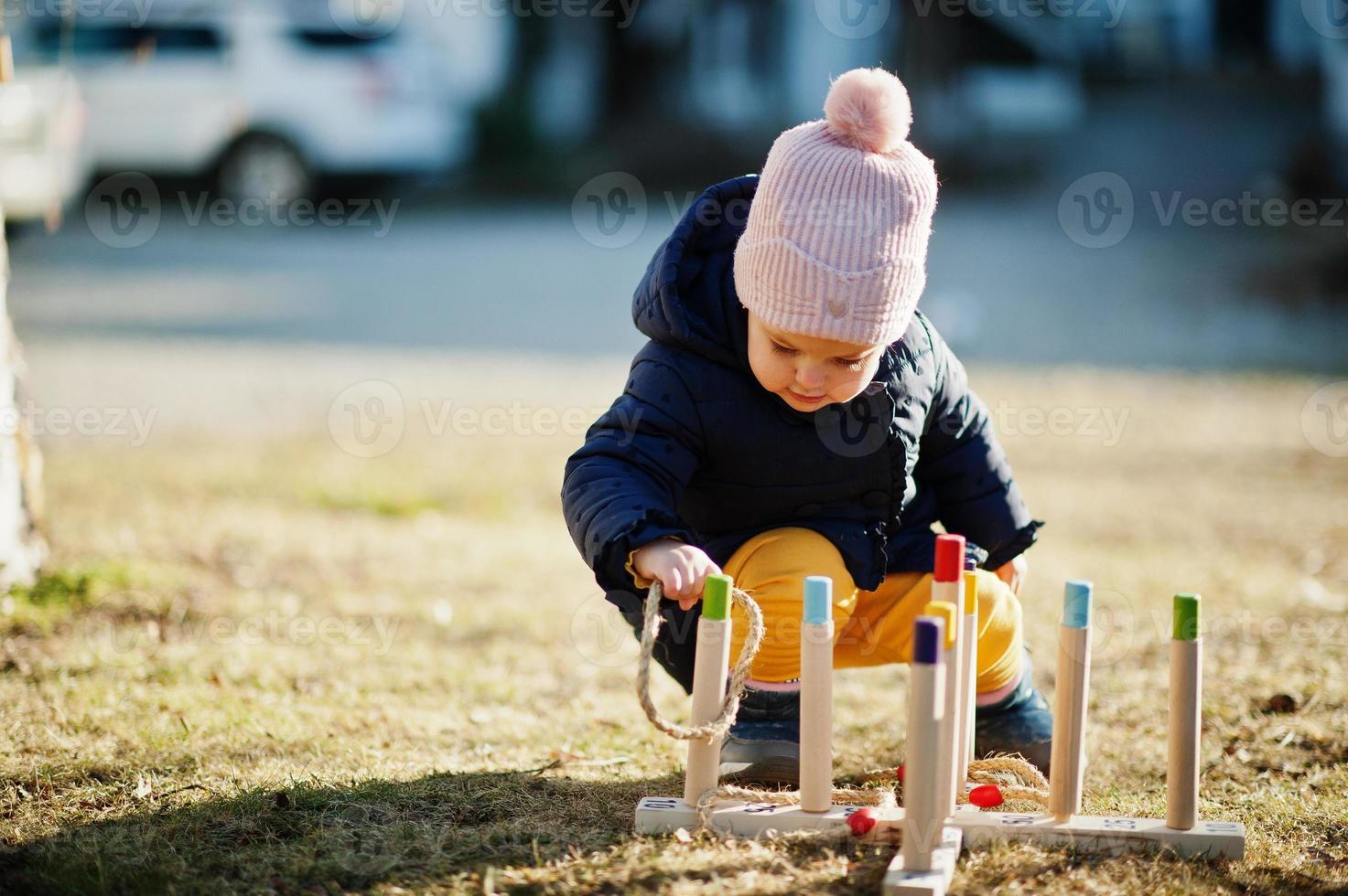 babymeisje speelt een spel gooien ring gooien buiten. foto